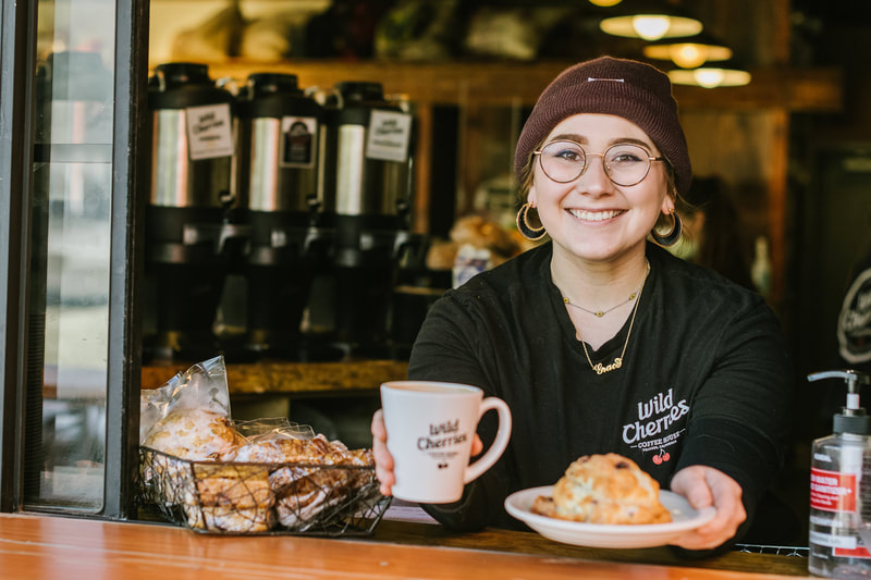 smiling barista serving coffee and pastry